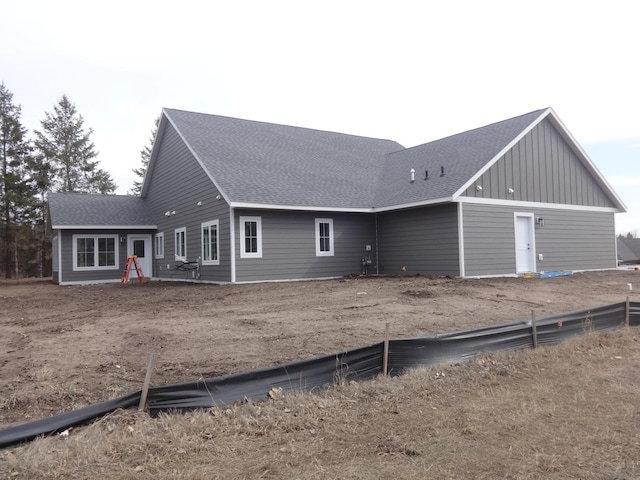 rear view of property with board and batten siding and a shingled roof