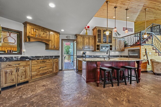 kitchen with stainless steel microwave, an island with sink, black oven, wooden ceiling, and stone counters