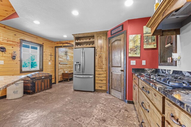 kitchen featuring wood walls, appliances with stainless steel finishes, and a textured ceiling