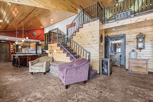 living room with sink, wood ceiling, high vaulted ceiling, and wooden walls