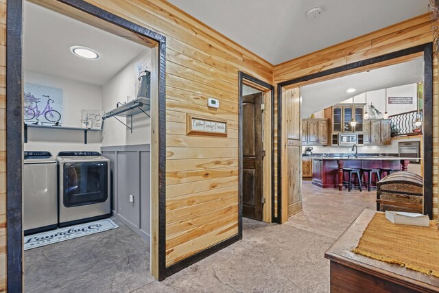 laundry area featuring washer and dryer, wooden walls, and sink