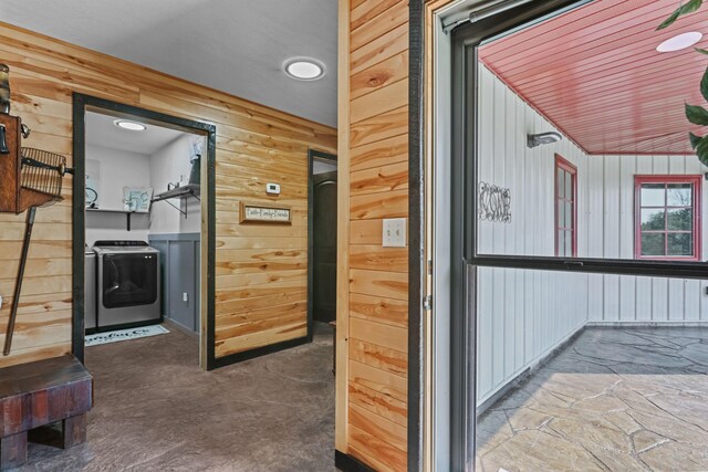 hallway with washer and clothes dryer and wood walls