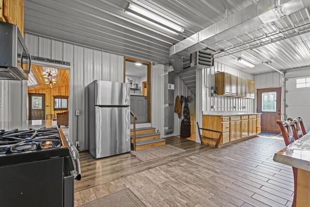 kitchen with a notable chandelier, wood walls, appliances with stainless steel finishes, and hardwood / wood-style floors