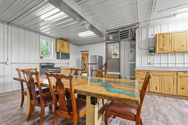 dining space with wood walls and light hardwood / wood-style flooring