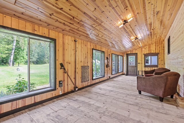 unfurnished room featuring wooden walls, wooden ceiling, vaulted ceiling, and light wood-type flooring