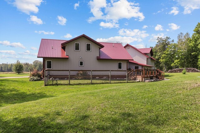 rear view of house featuring a wooden deck and a lawn