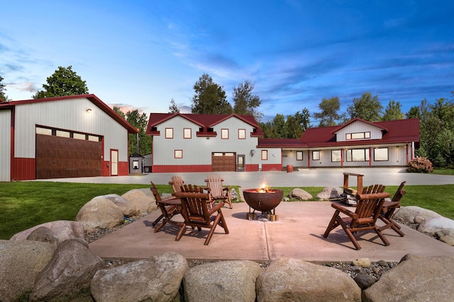 patio terrace at dusk featuring a garage and a lawn