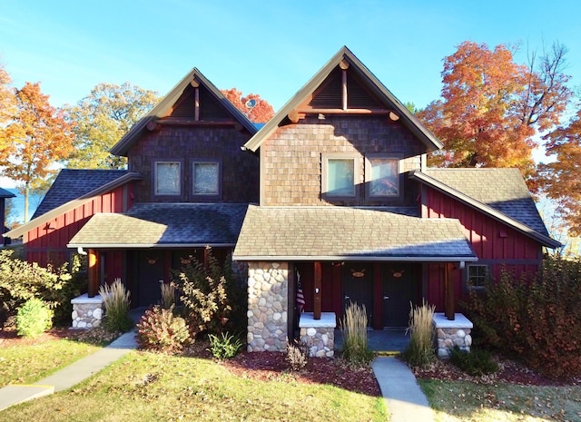 view of front facade featuring covered porch, board and batten siding, a shingled roof, and stone siding