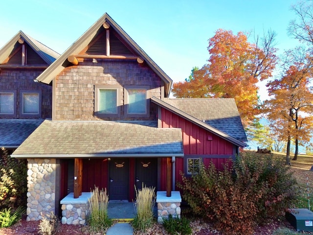 view of front facade with a shingled roof, board and batten siding, and a porch