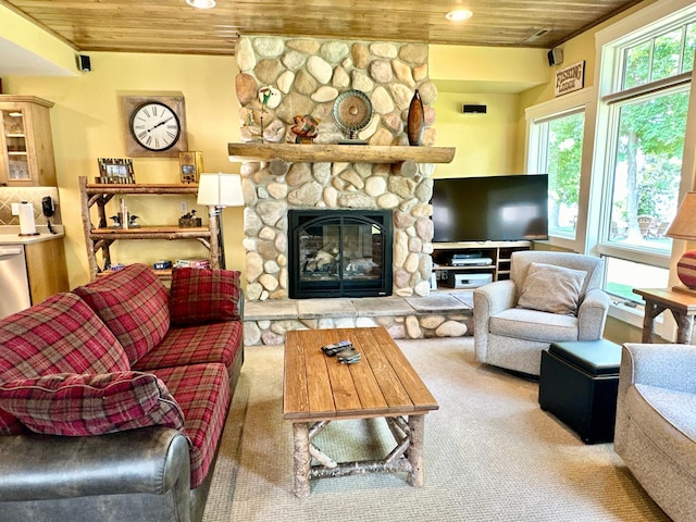 living room featuring a stone fireplace, carpet flooring, wooden ceiling, and a wealth of natural light