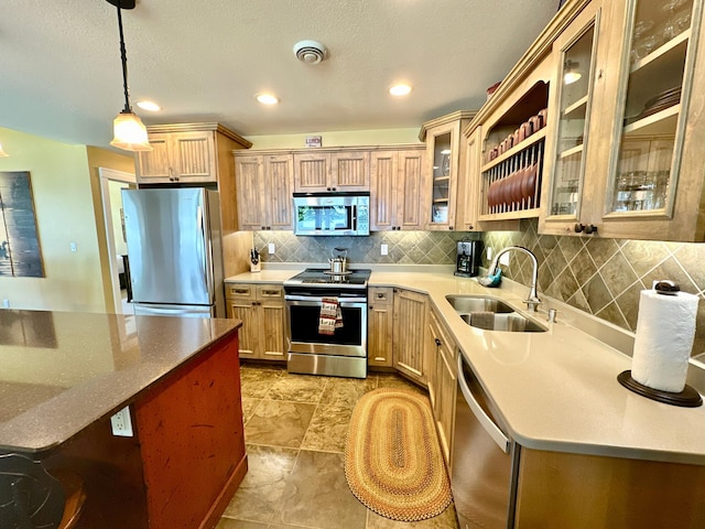 kitchen with a sink, stainless steel appliances, backsplash, glass insert cabinets, and hanging light fixtures