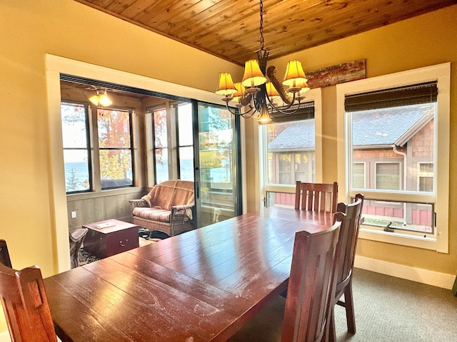 carpeted dining area with a wealth of natural light, a notable chandelier, and wooden ceiling