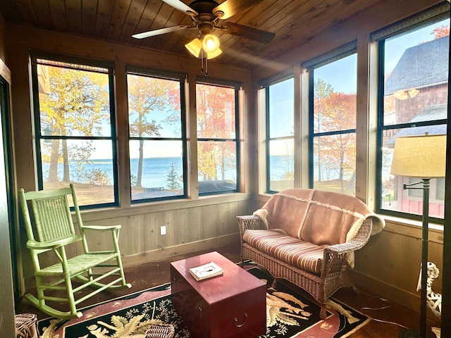 sunroom / solarium featuring baseboards, a water view, wood ceiling, and wood finished floors