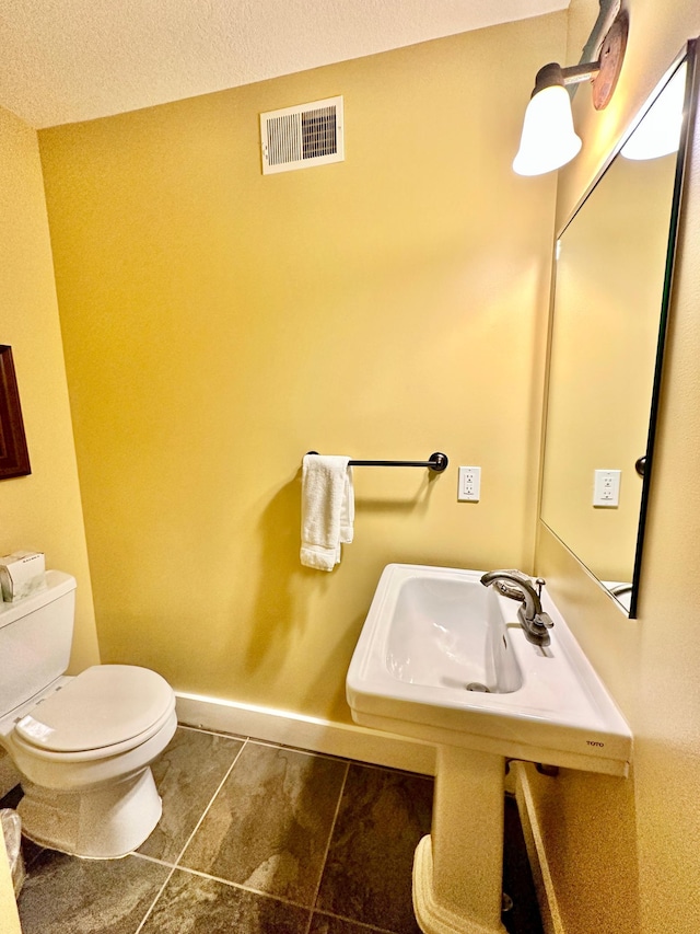 bathroom featuring toilet, a textured ceiling, and tile patterned flooring