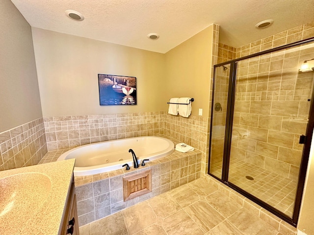 bathroom with a textured ceiling, a whirlpool tub, a shower stall, tile patterned floors, and vanity