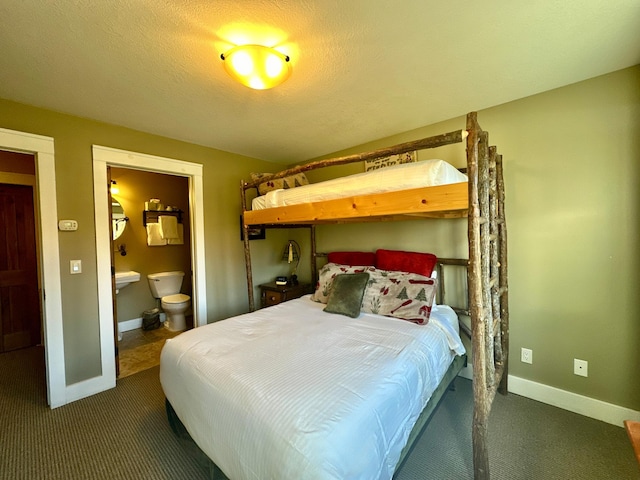 bedroom featuring dark carpet, a textured ceiling, and ensuite bath