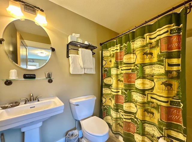 bathroom featuring sink, a shower with shower curtain, and toilet