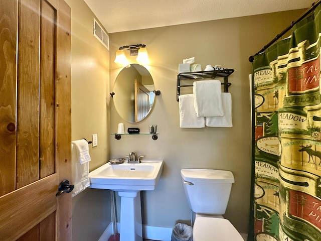 bathroom with toilet, a shower with shower curtain, and visible vents