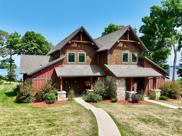 craftsman-style home with a front yard, a porch, roof with shingles, and board and batten siding