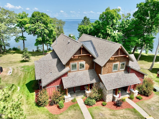view of front of property with a water view, board and batten siding, a front yard, a porch, and roof with shingles