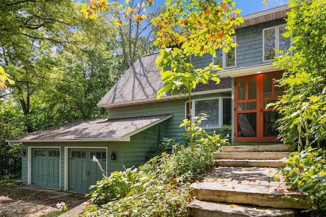 view of side of property with entry steps and roof with shingles