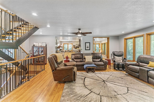 living area featuring a textured ceiling, recessed lighting, stairs, and light wood-style floors