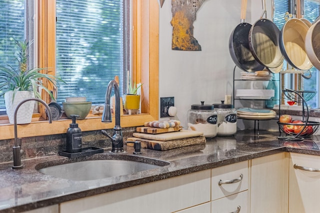 kitchen featuring dark stone counters, a sink, and a healthy amount of sunlight