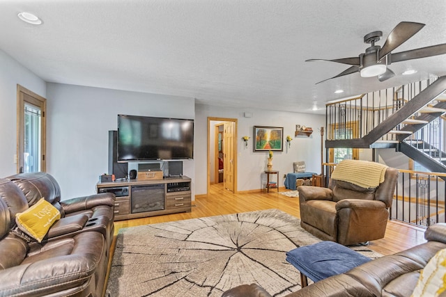 living room featuring plenty of natural light, a textured ceiling, light wood finished floors, and stairs