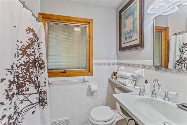 full bath featuring toilet, tile walls, visible vents, and a sink