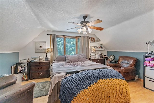 bedroom featuring a ceiling fan, vaulted ceiling, a textured ceiling, and light wood finished floors