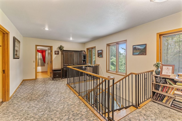 corridor with baseboards, carpet flooring, and an upstairs landing