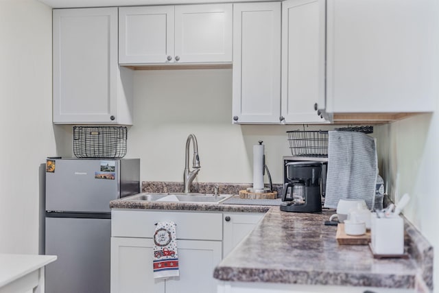 kitchen featuring white cabinetry, a sink, and freestanding refrigerator