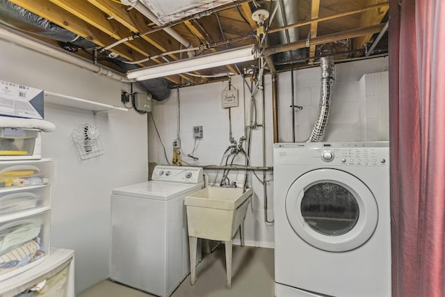 laundry room with laundry area, independent washer and dryer, and concrete block wall