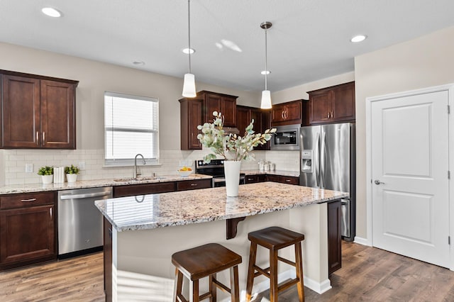 kitchen featuring wood finished floors, appliances with stainless steel finishes, a sink, and dark brown cabinetry