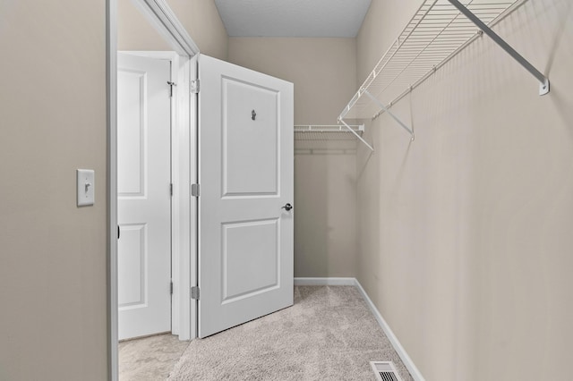 spacious closet with visible vents and light colored carpet