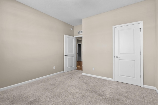 unfurnished bedroom with carpet, visible vents, and baseboards