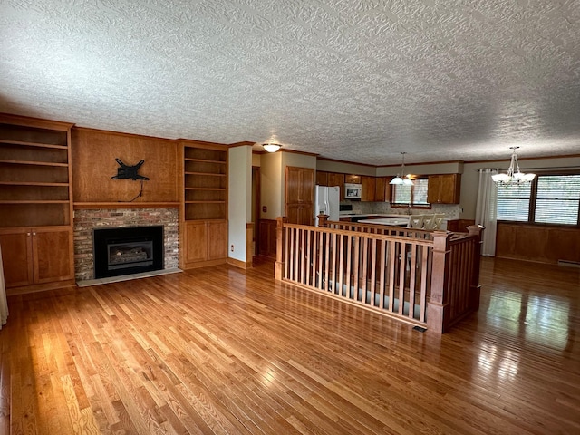 unfurnished living room featuring a chandelier, a textured ceiling, and hardwood / wood-style flooring