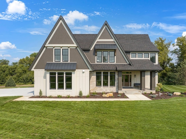 view of front facade featuring stone siding, a front lawn, board and batten siding, and a shingled roof