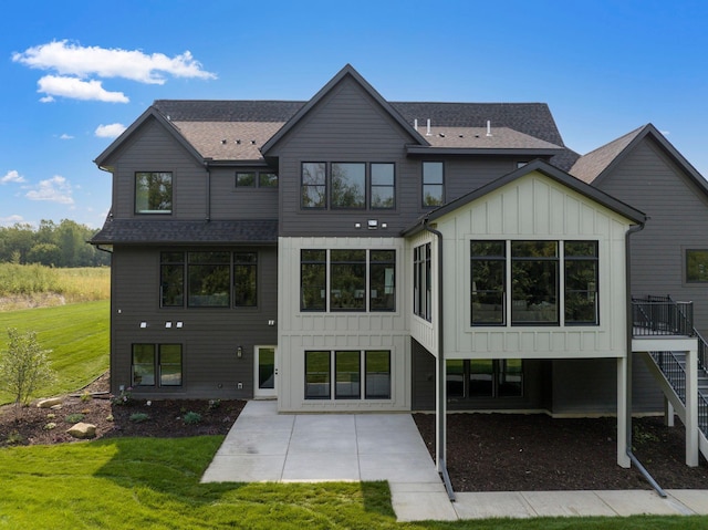 rear view of property featuring a yard, board and batten siding, and roof with shingles