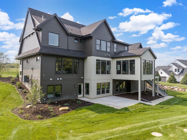 back of house with a yard, a shingled roof, board and batten siding, a patio area, and stairs