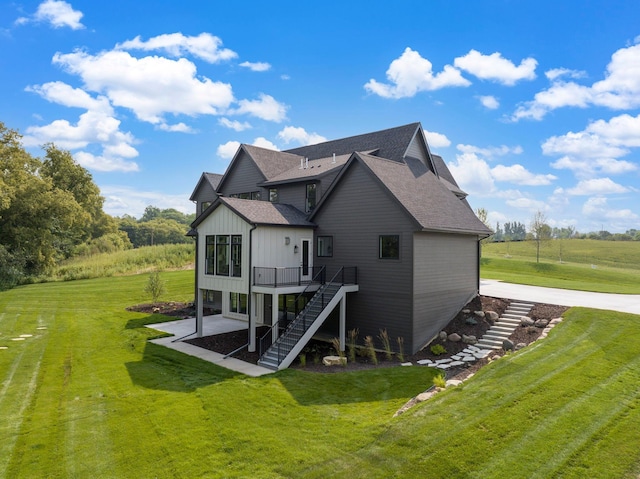 back of property featuring board and batten siding, a lawn, and stairway