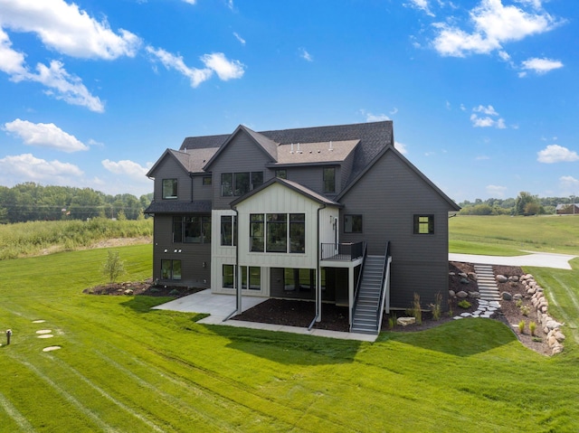 rear view of property featuring a yard, stairway, board and batten siding, a patio area, and a wooden deck