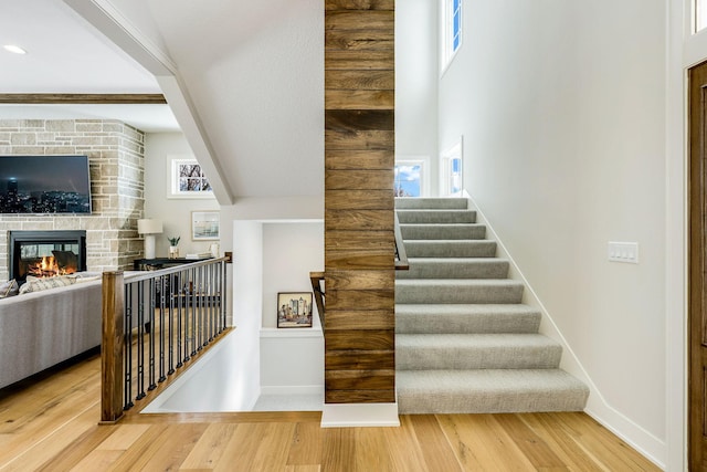 stairway with a fireplace, baseboards, and wood finished floors