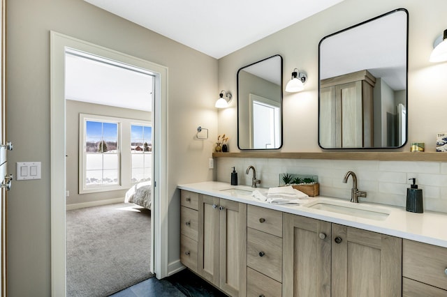 ensuite bathroom with baseboards, a sink, decorative backsplash, and double vanity