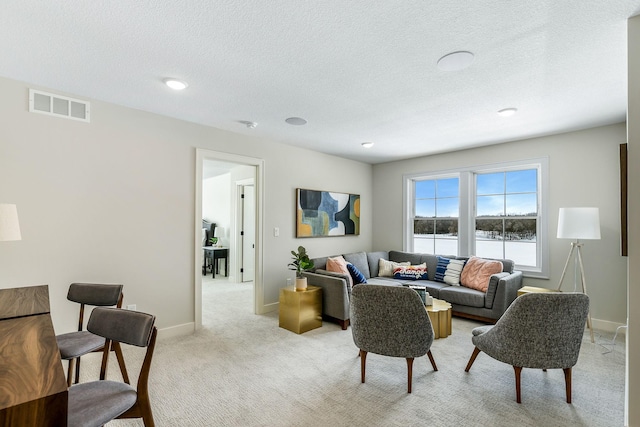 living room featuring light carpet, a textured ceiling, visible vents, and baseboards