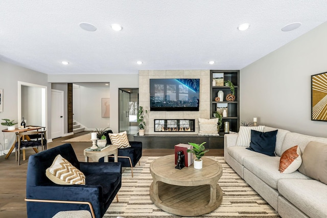 living area featuring recessed lighting, stairs, a tiled fireplace, and wood finished floors