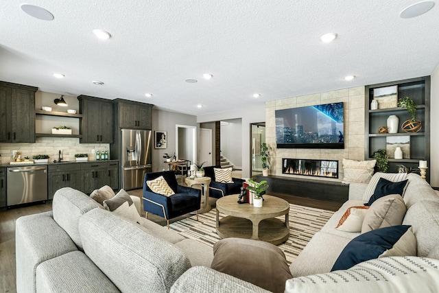 living room featuring recessed lighting, stairway, a textured ceiling, wood finished floors, and a tile fireplace