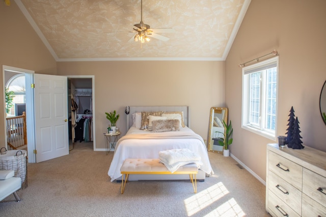 carpeted bedroom featuring crown molding, vaulted ceiling, a spacious closet, and ceiling fan