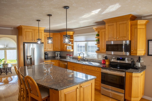 kitchen featuring appliances with stainless steel finishes, a kitchen island, light hardwood / wood-style floors, and a healthy amount of sunlight