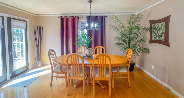 dining area featuring wood-type flooring, crown molding, and a textured ceiling